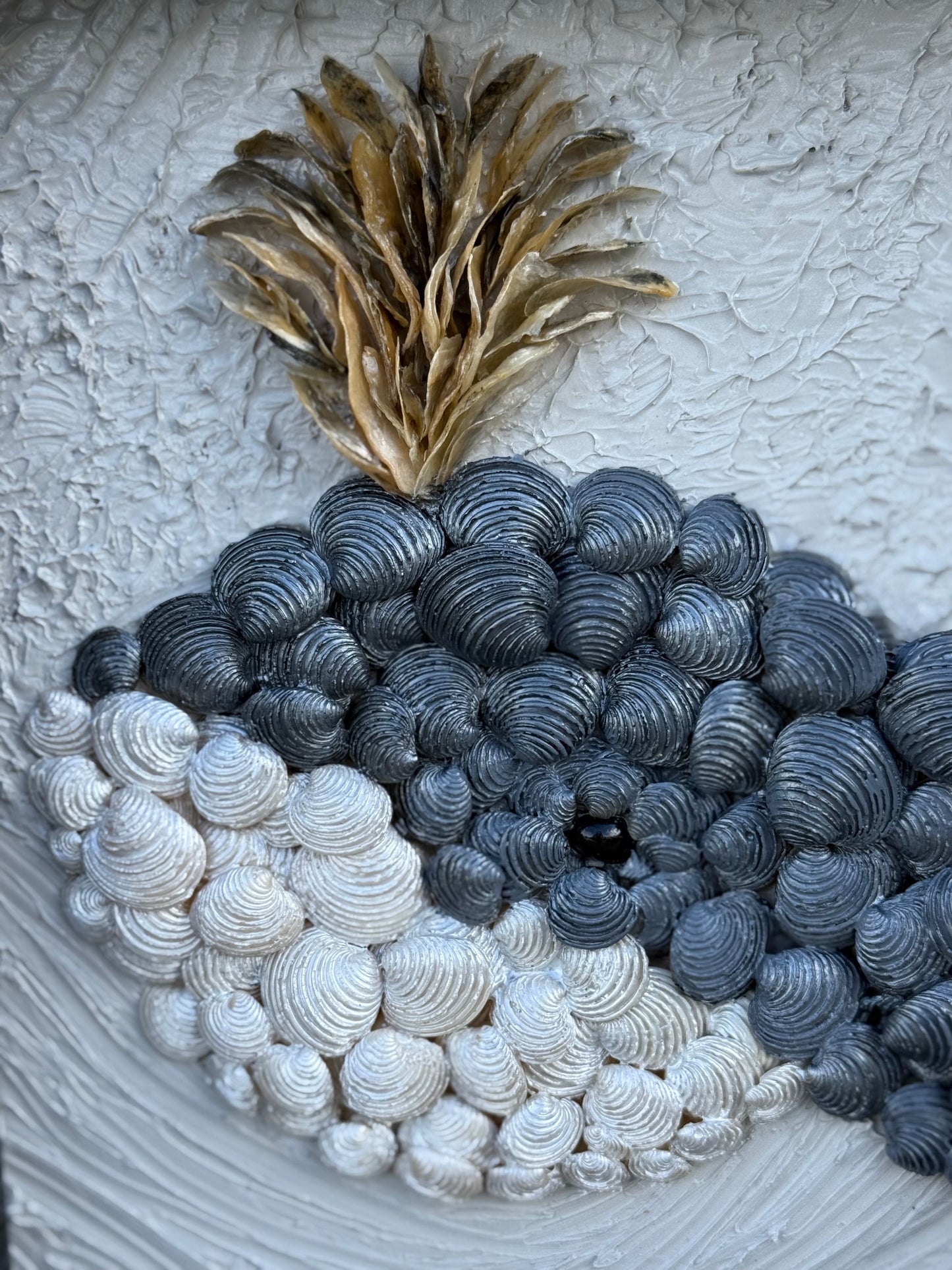 Close up of baby whale created from shells and set in a frame with textured background.
