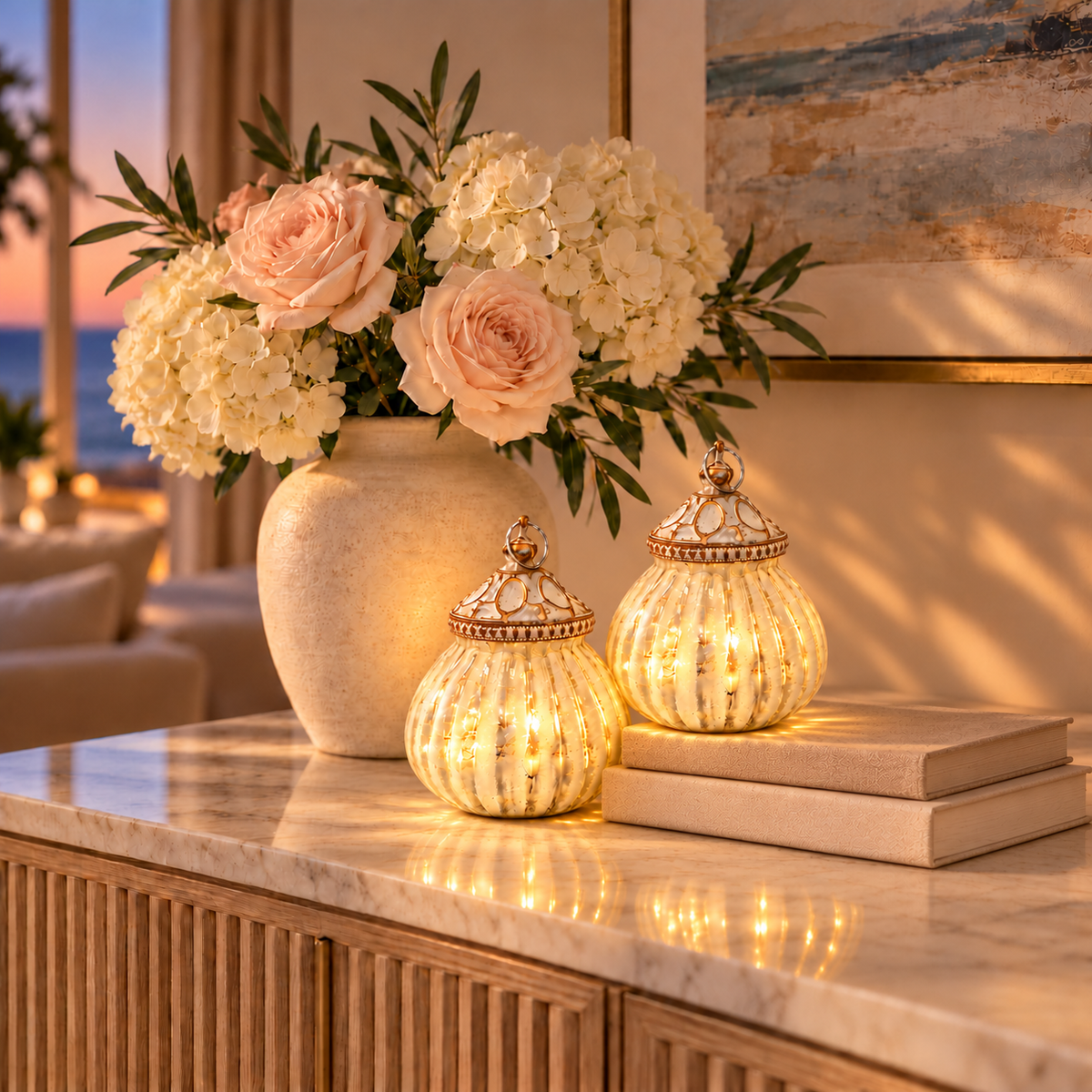 Styling mockup: two matching illuminated Balle White LED Lanterns grouped closely, one on books and one on marble, beside flowers; accessories not included