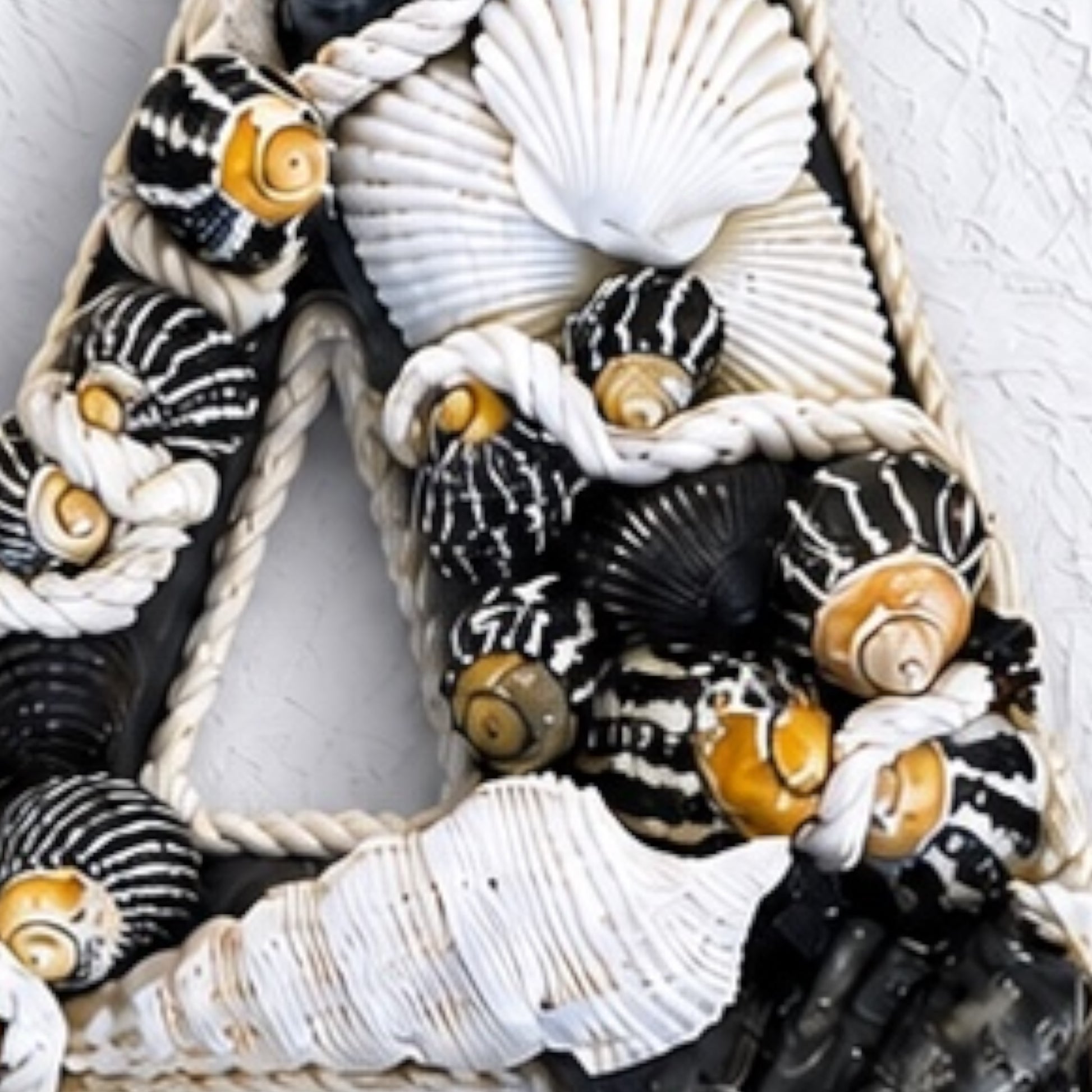 Detailed view of handmade shell art initial created with black and white natural seashells, a personalised coastal keepsake for nursery or bedroom decor. Available in all letters and made to order.